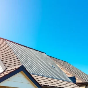 A house featuring various roofing materials under a sunny sky